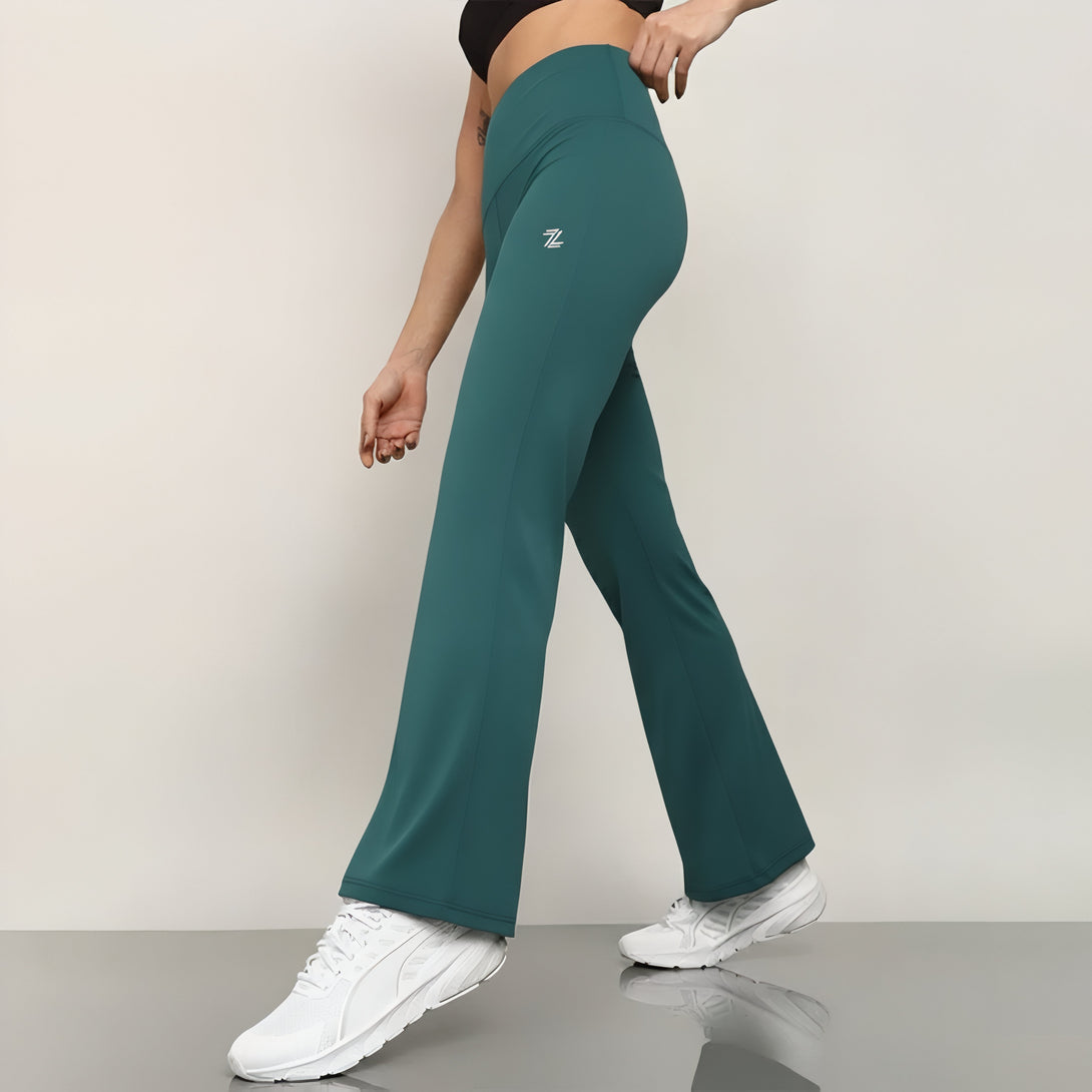 Person wearing teal flared pants with a logo on a plain background